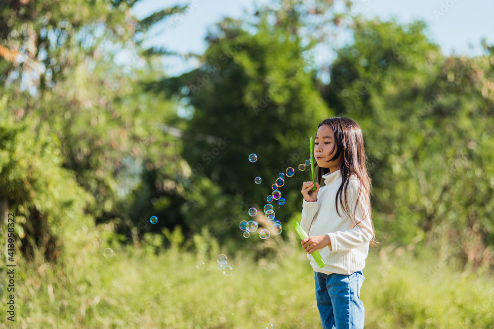 Happy Asian little cute girl child having fun and enjoying outdoor play blowing soap bubbles during in the garden park on a sunny day, summer time Happy Asian little cute girl child having fun and enjoying outdoor play blowing soap bubbles during in the garden park on a sunny day, summer time