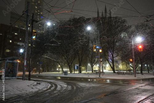 Urban cityscape during night time with city streets during snowstorm in the winter