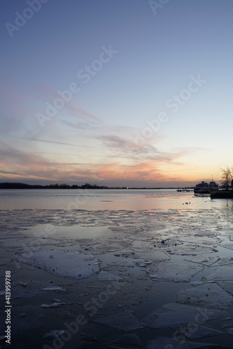 Waterfront sunset during winter time with frozen lake and beautiful sunset colours