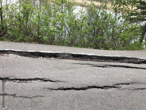 Dark cracked asphalt road due to heat, water, and cold damage