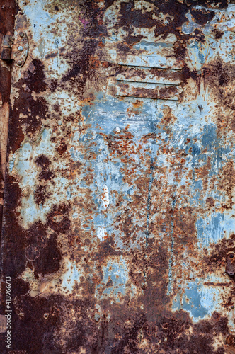 Brown rust, scratched peeled off blue paint. Door made rusty shabby sheet metal. Textured rough metal surface, rusty metal structure.