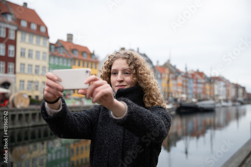 Canvas Print Tourist girl takes a selfie in Nyhavn in central Copenhagen.