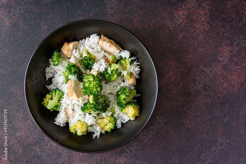 Black food bowl with steamed rice, roasted broccoli and grilled check breast
