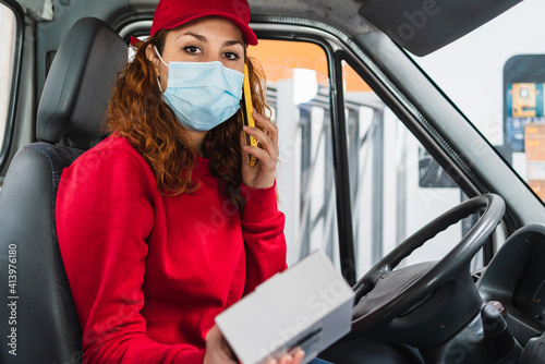 Female delivery driver with a medical mask calling a person about their package