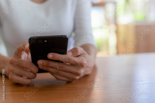 Close up hands of beautiful young woman holding mobile, smart phone sitting in cafe. Soft focus hands of women holding and use cell phone in coffee shop. Tectechnology and lifestyle concept.
