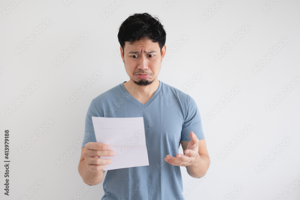 Asian man is sad and shocked by the letter in his hand on isolated background. Asian man is sad and shocked by the letter in his hand on isolated background.