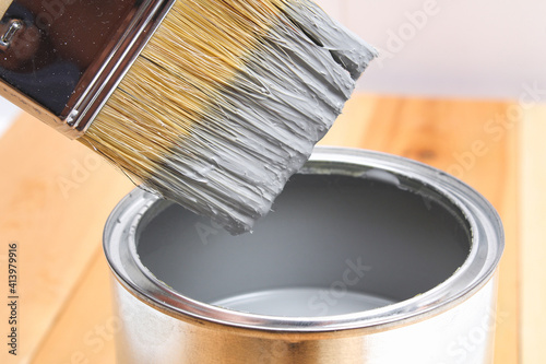 Fototapeta Naklejka Na Ścianę i Meble -  Brush with can paint in hand. A man paints wooden boards in a gray paint brush.
