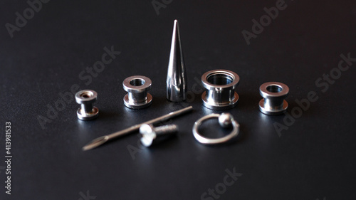 Set for piercing on a dark background, ear tunnels, tunnels and earrings for the ears and tongue closeup