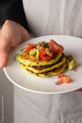 squash pancakes with tomato salsa in male hands
