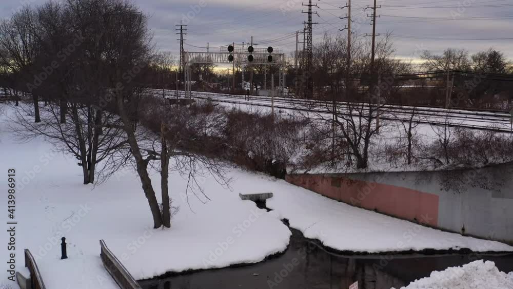 An aerial view of train tracks and power lines in the morning, after a snow storm. The drone camera boom by a stream on a cloudy morning and there is snow everywhere. An aerial view of train tracks and power lines in the morning, after a snow storm. The drone camera boom by a stream on a cloudy morning and there is snow everywhere.