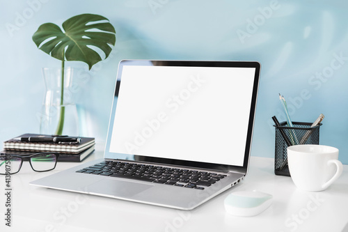 Modern and stylish workspace mock up with blank laptop and desk office supplies with color background and copy space