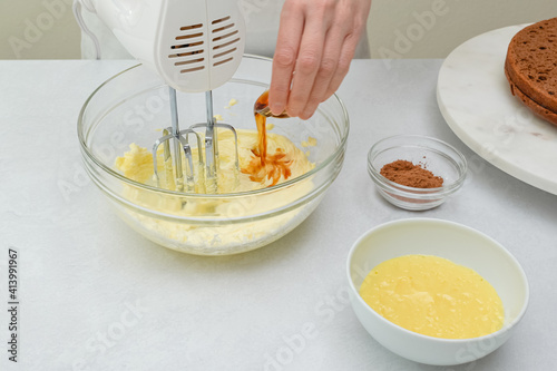 Foto Woman hands beating butter and vanilla extract in a glass bowl using an electric hand mixer, close up view