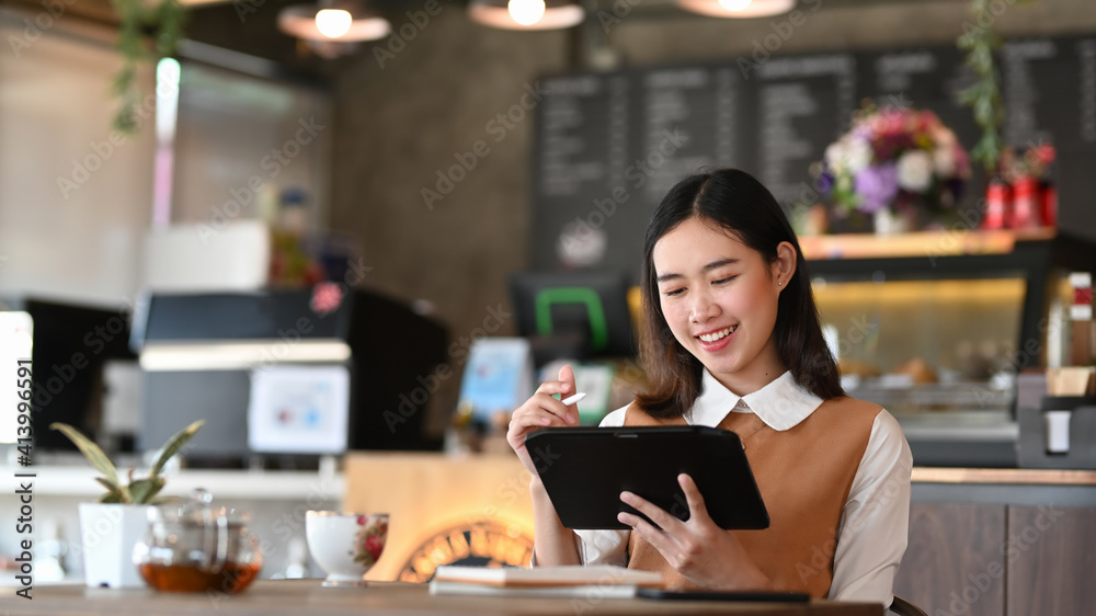 Smiling young female freelance working on digital tablet and sitting in modern coffee shop. Smiling young female freelance working on digital tablet and sitting in modern coffee shop.