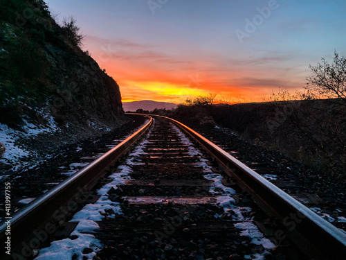 Sunset over railroad reflecting on the rails disapearing around a curve © Shannon