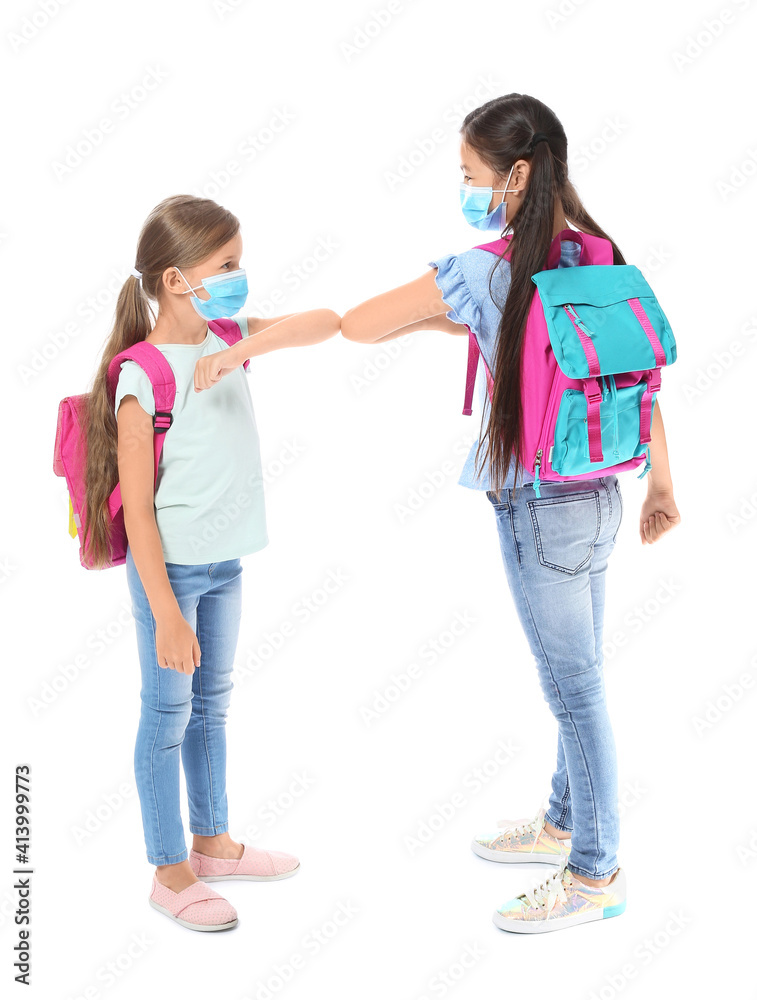 Little schoolchildren in medical masks greeting each other on white background. Coronavirus epidemic Little schoolchildren in medical masks greeting each other on white background. Coronavirus epidemic