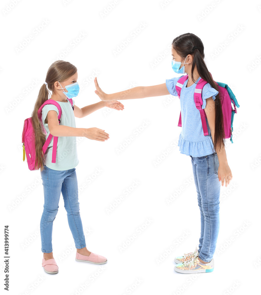 Little schoolgirl in medical mask refusing to hugging her friend against white background. Coronavirus epidemic Little schoolgirl in medical mask refusing to hugging her friend against white background. Coronavirus epidemic