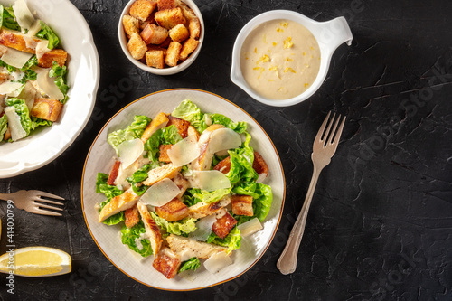 Chicken Caesar salad, shot from above with croutons and the classic dressing, on a black background with a place for text