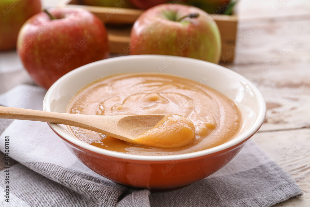 Bowl and spoon with sweet apple jam on wooden background Bowl and spoon with sweet apple jam on wooden background