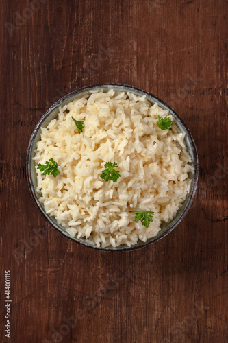 Rice, overhead shot on a rustic wooden table, with fresh parsley leaves and a place for text