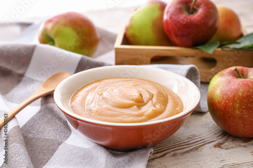 Bowl with sweet apple jam on wooden background