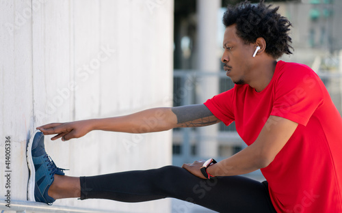 Afro athletic man stretching arms before exercise.