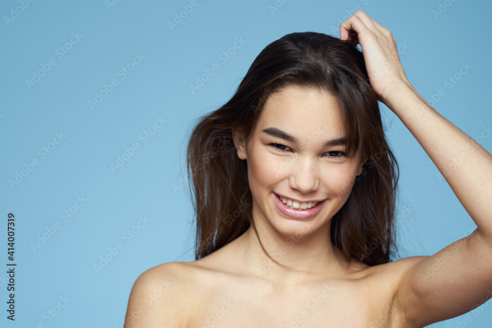 brunette with bare shoulders cosmetics close-up skin care blue background brunette with bare shoulders cosmetics close-up skin care blue background
