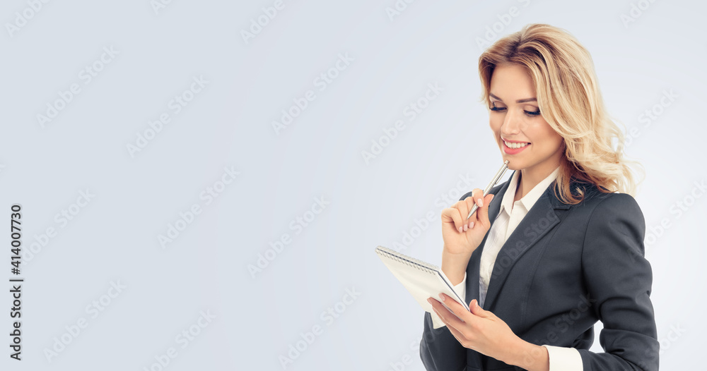 Businesswoman with notepad writing, isolated over grey background. Business success concept. Copy space empty area for some text message or slogan. Businesswoman with notepad writing, isolated over grey background. Business success concept. Copy space empty area for some text message or slogan.