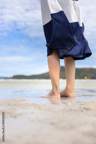 Woman barefoot walking on summer along wave of sea water and sand on the beach. © Charnchai saeheng