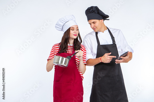 Cooking. Cooking a meal together. A young couple is preparing lunch. A man and a woman prepare food according to a recipe. Electronic cookbook.