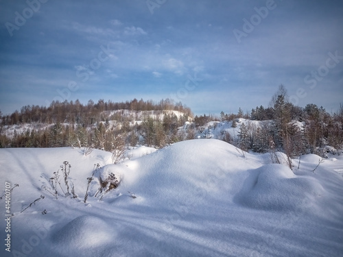 Winter landscape sunset in the forest with snowy field in the foreground.