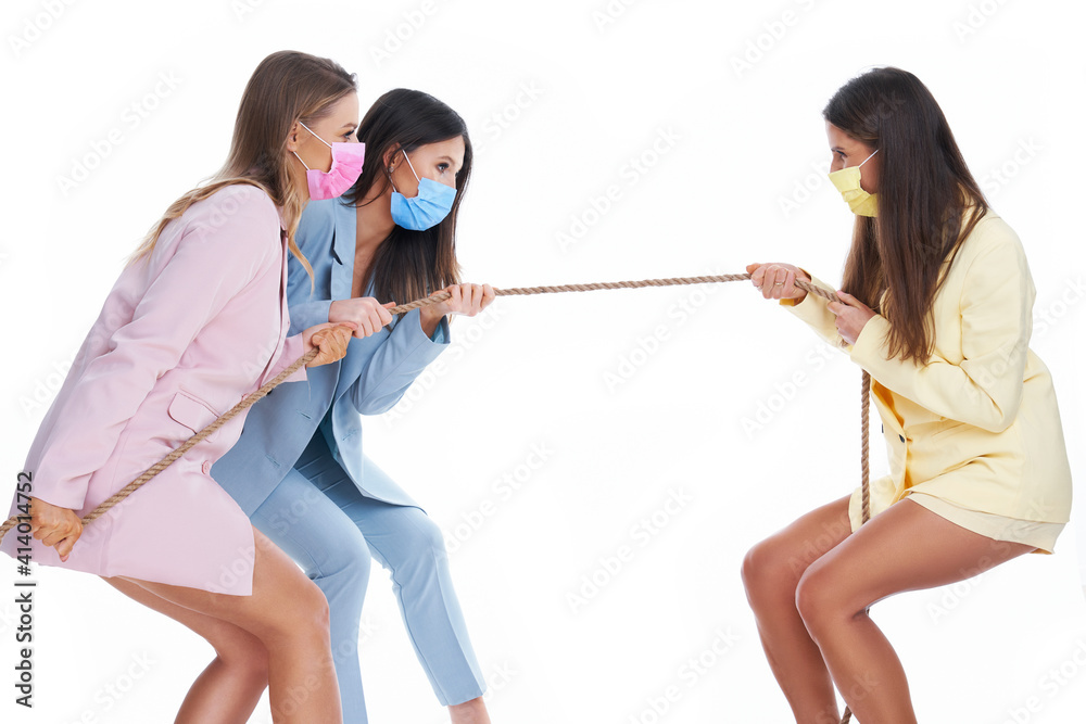 Three women in pastel suits pulling rope over white background Three women in pastel suits pulling rope over white background