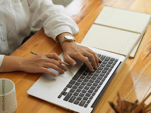 Female hands typing on laptop keyboard on study table with stationery