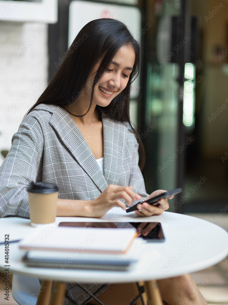 Businesswoman smiling and relaxing with smartphone while working in garden at home Businesswoman smiling and relaxing with smartphone while working in garden at home