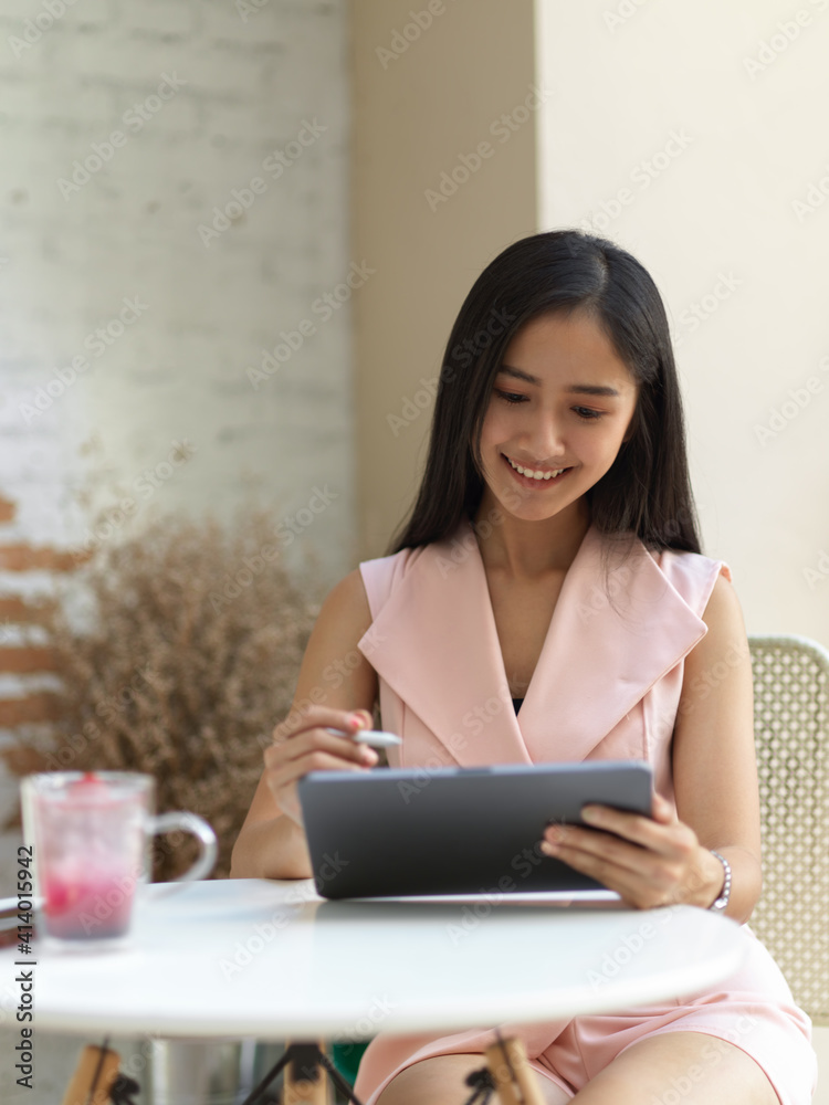 Female teenager relaxing with digital tablet and beverage on coffee table in cafe Female teenager relaxing with digital tablet and beverage on coffee table in cafe