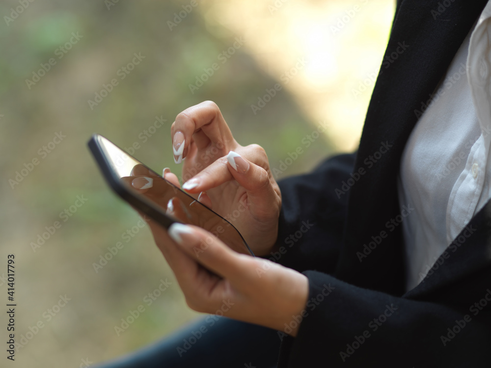 Businesswoman texting message on smartphone while relaxing at outdoor