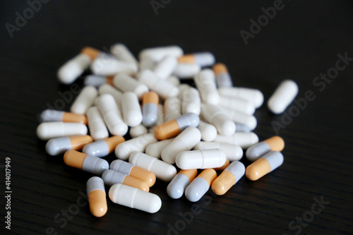 Pills on a dark wooden table, variety of medications in capsules. Background for pharmacy, antibiotics, vitamins 