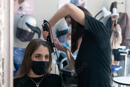 Young hairdresser combing her client's hair