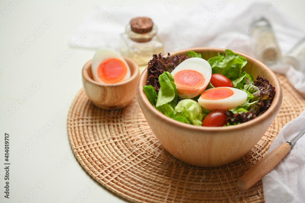 A bowl of of salad with boiled eggs, lettuce and tomato on wicker placemat A bowl of of salad with boiled eggs, lettuce and tomato on wicker placemat