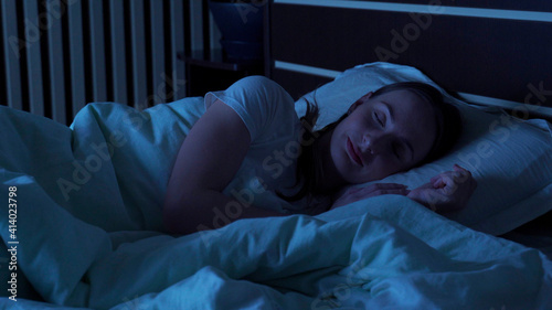 Tableau sur toile Young woman comfortably sleeping at night in a bed at home