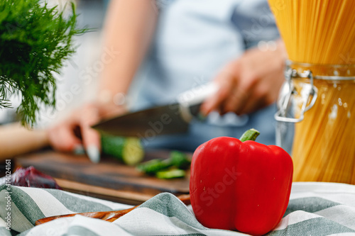 Unrecognizable woman cutting cucumber on wooden board close up