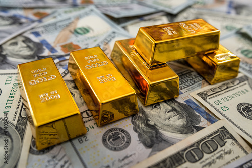 Gold bullion on pile us dollar bills as background