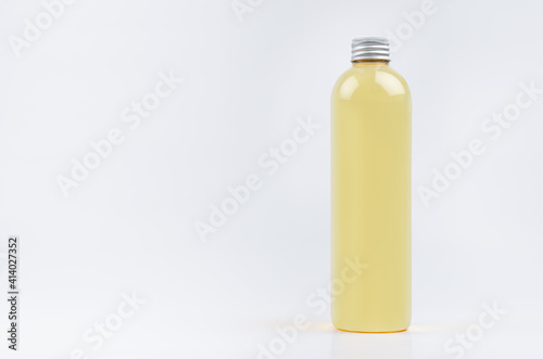 Transparent plastic tall thin bottle with orange drink, cooking oil or cosmetic produce, silver cap mockup on white background. Template for design.