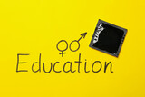 Text Education and condom on yellow background