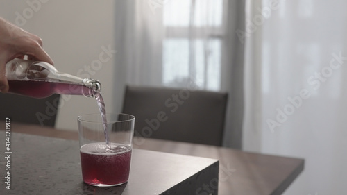 pour purple drink in tumbler glass on concrete countertop with copy space
