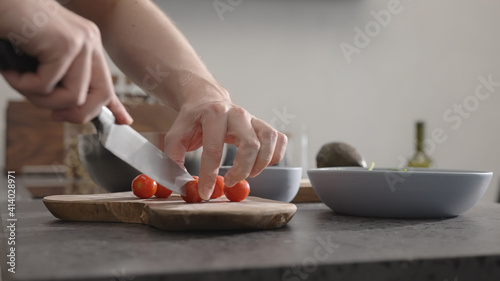 man cut cherry tomato for salad on kitchen countertop
