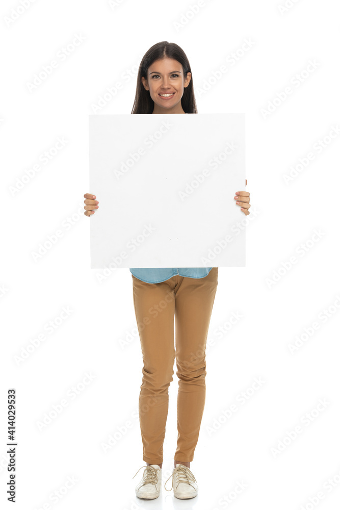 young casual woman showing a blank billboard at the camera young casual woman showing a blank billboard at the camera