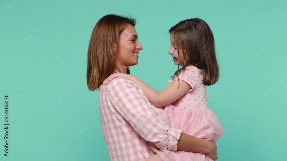Happy woman in pink clothes have fun with cute child baby girl 5-6 years old. Mommy holds on hands hugs little kid daughter isolated on pastel blue background studio. Mother's Day love family concept Happy woman in pink clothes have fun with cute child baby girl 5-6 years old. Mommy holds on hands hugs little kid daughter isolated on pastel blue background studio. Mother's Day love family concept