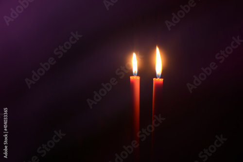 Burning candles at Night. Two red candles on dark purple background.