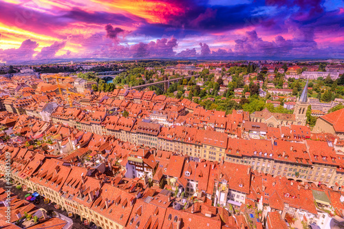 Amazing colorful sunset sky with clouds of Bern old town in Switzerland, UNESCO World Heritage Site from Cathedral bell tower. Aerial view of skyline cityscape of medieval city at twilight.