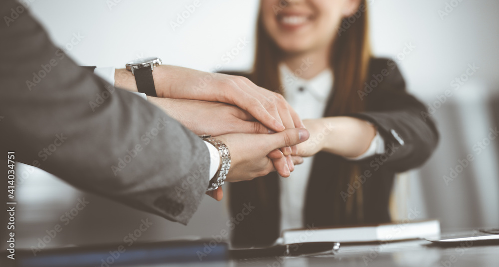 Unknown business people group joining hands in modern office. Businessmen and women making circle with their hands as a team, close-up